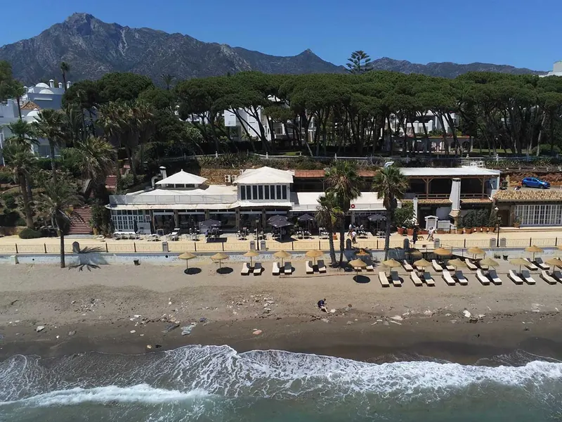 Aerial view of Corocoro on the beach with the Marbella mountains behind