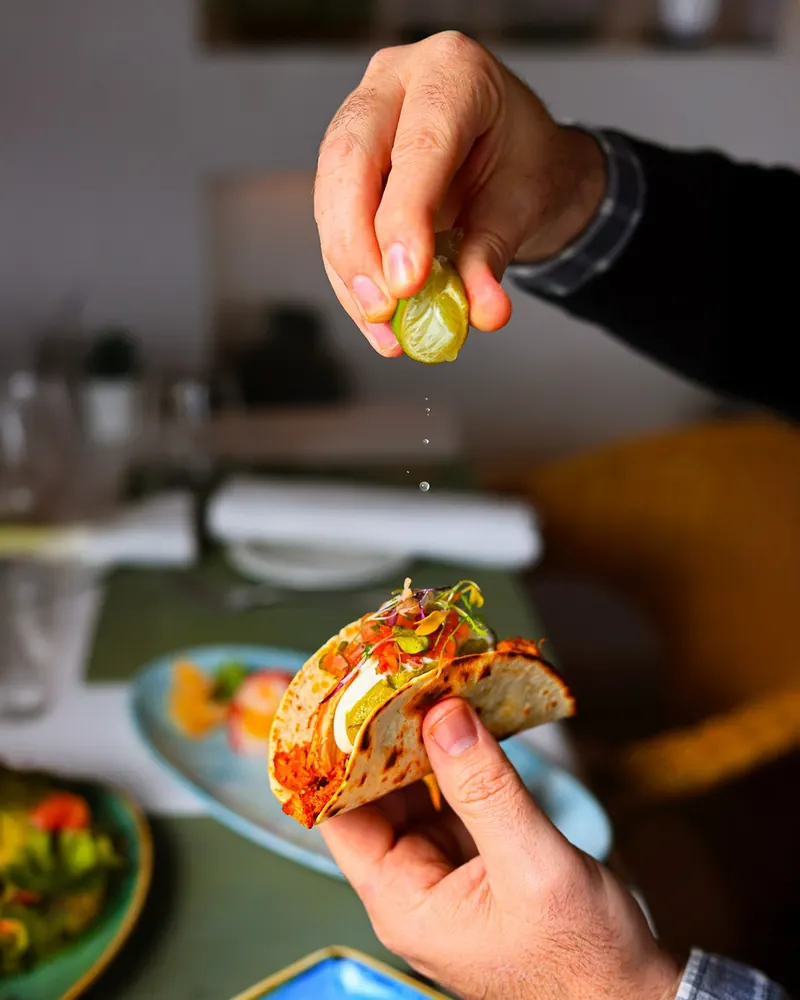 A chef finishing a taco with a squeeze of lime